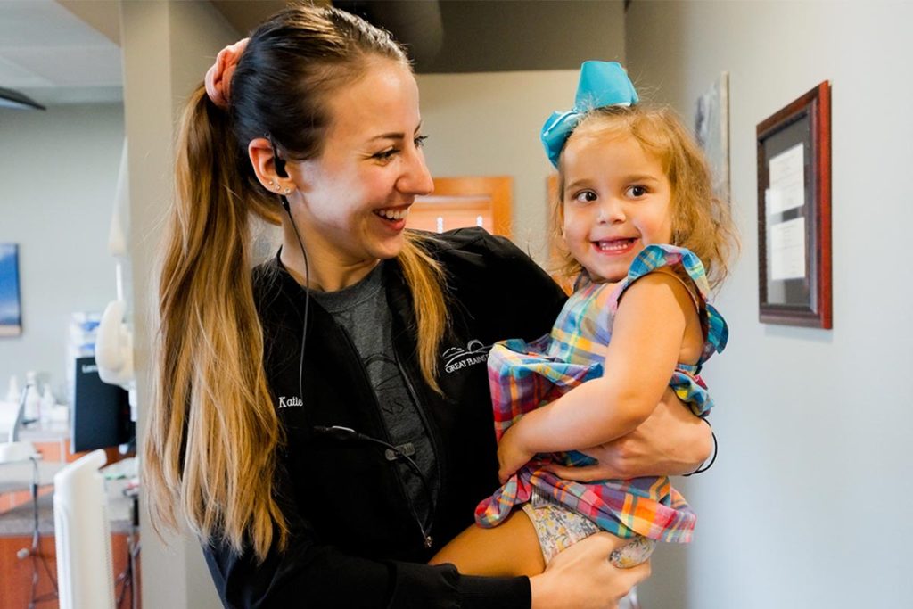 Employee Katie holds a child in the Great Plains Dental office in Sioux Falls